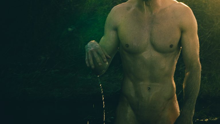 Un homme nu sors de l'eau dans la pénombre